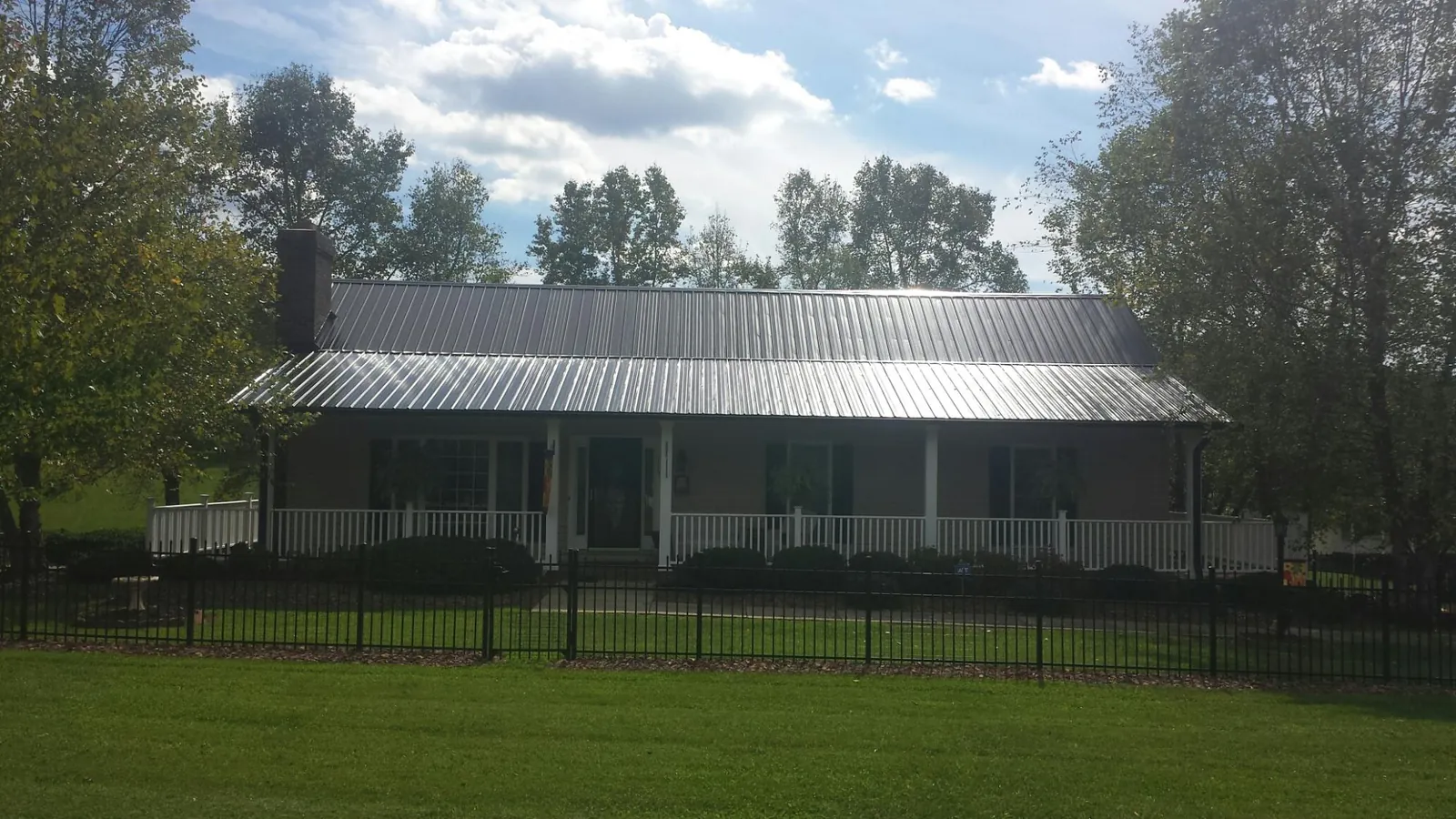 Gray metal roof on a brick ranch with a full width front porch — Gutter Guard Installation work by our crew in Gillette