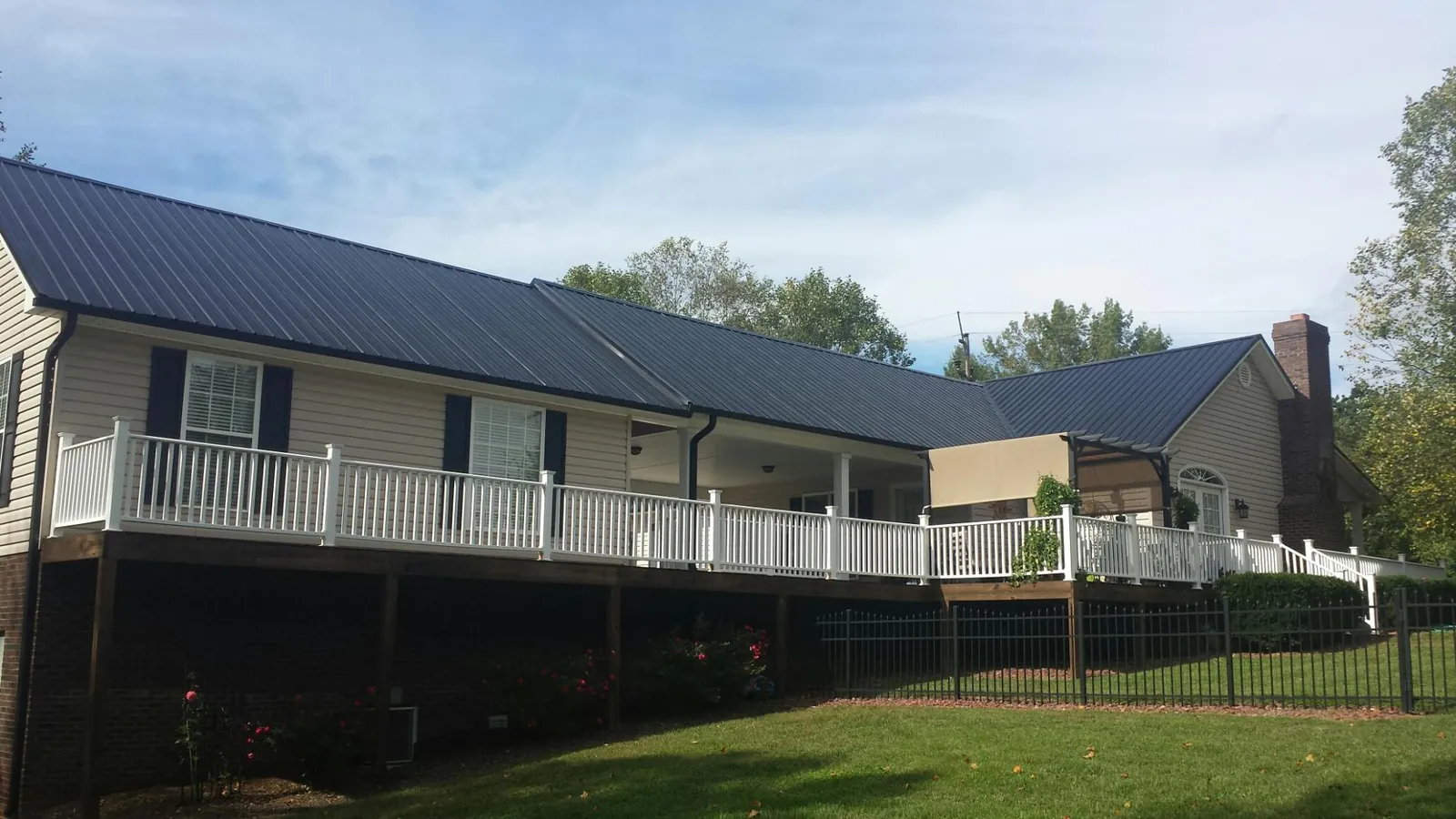 Black metal roof above a long white railed deck on a hillside home in Gillette