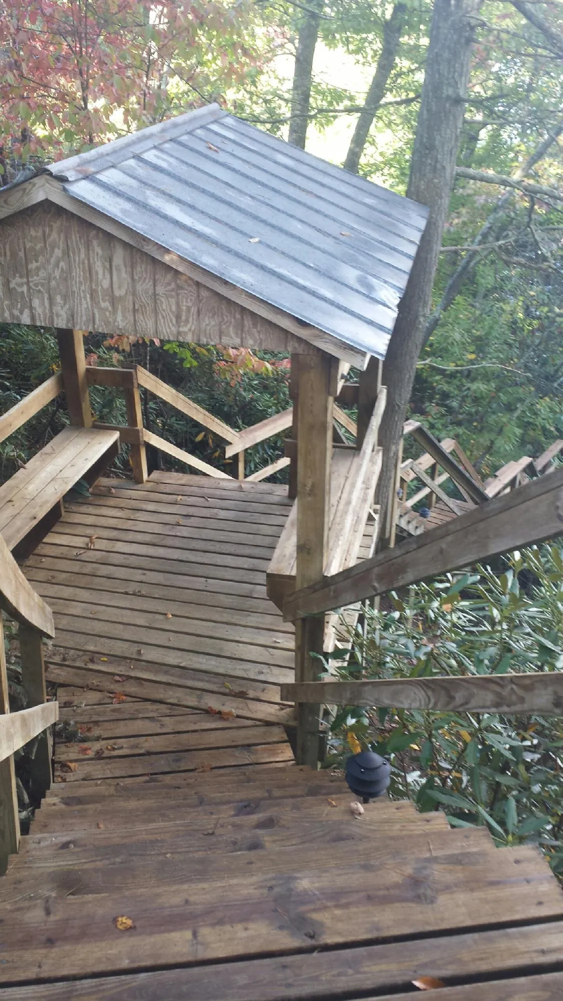 Metal roofed shelter over wooden steps on a wooded walkway — Skylight Repair & Installation work by our crew in Gillette