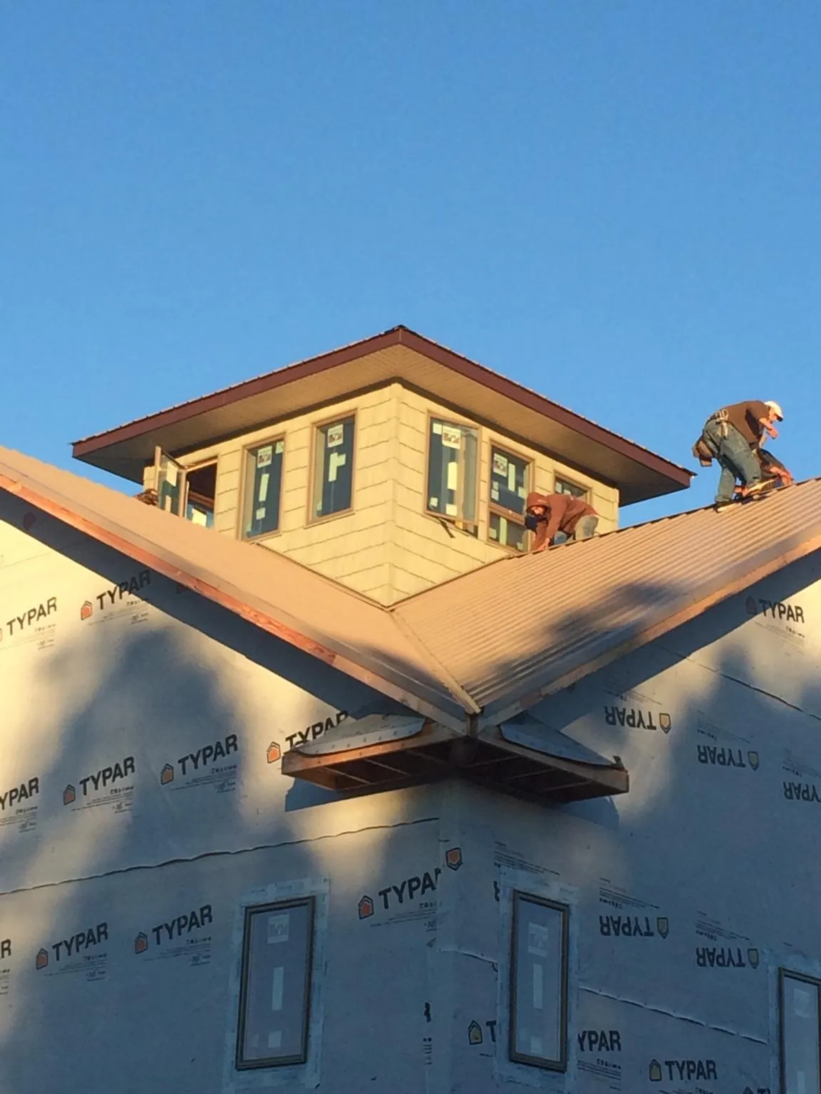 Roofers working around a rooftop cupola on a new metal roof at sunset — Roof Waterproofing in Gillette by Roofing Brothers